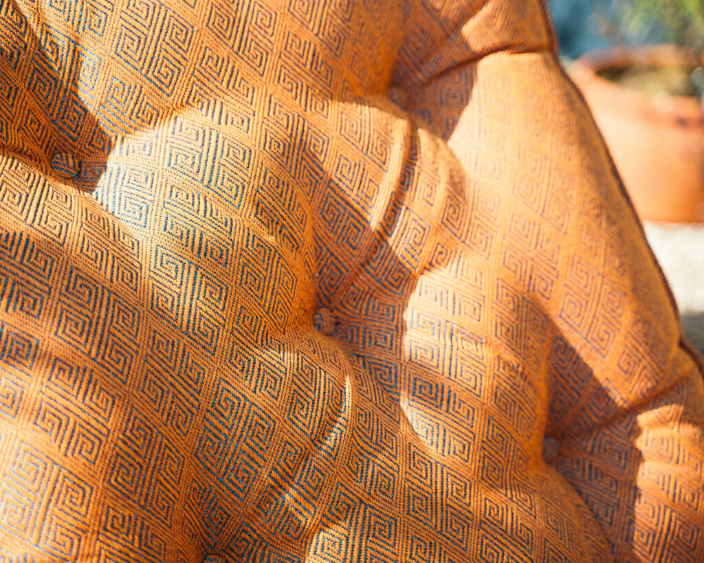 Close-up of an orange outdoor cushion with a geometric pattern, highlighting bold and stylish upholstery trends for 2025 outdoor furniture.